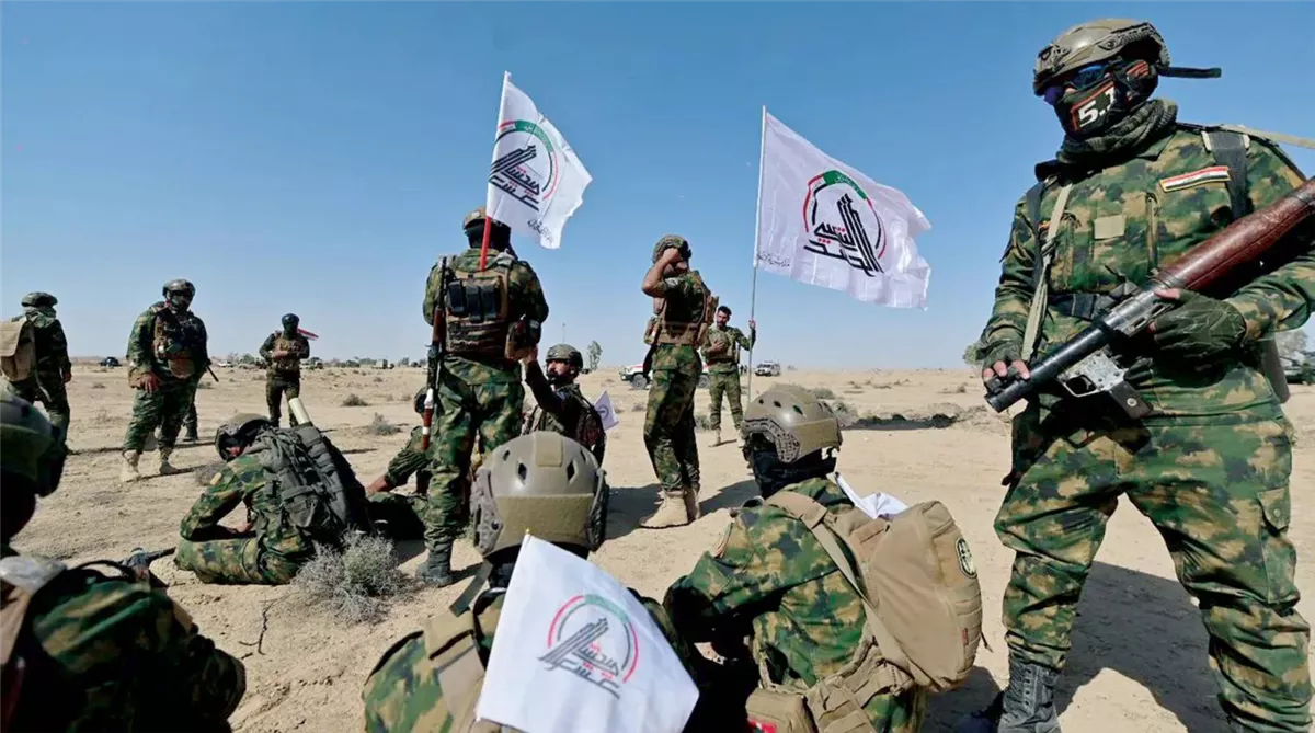 مقاتلون يرفعون شعار الحشد الشعبي خلال تدريبات عسكرية في العراق