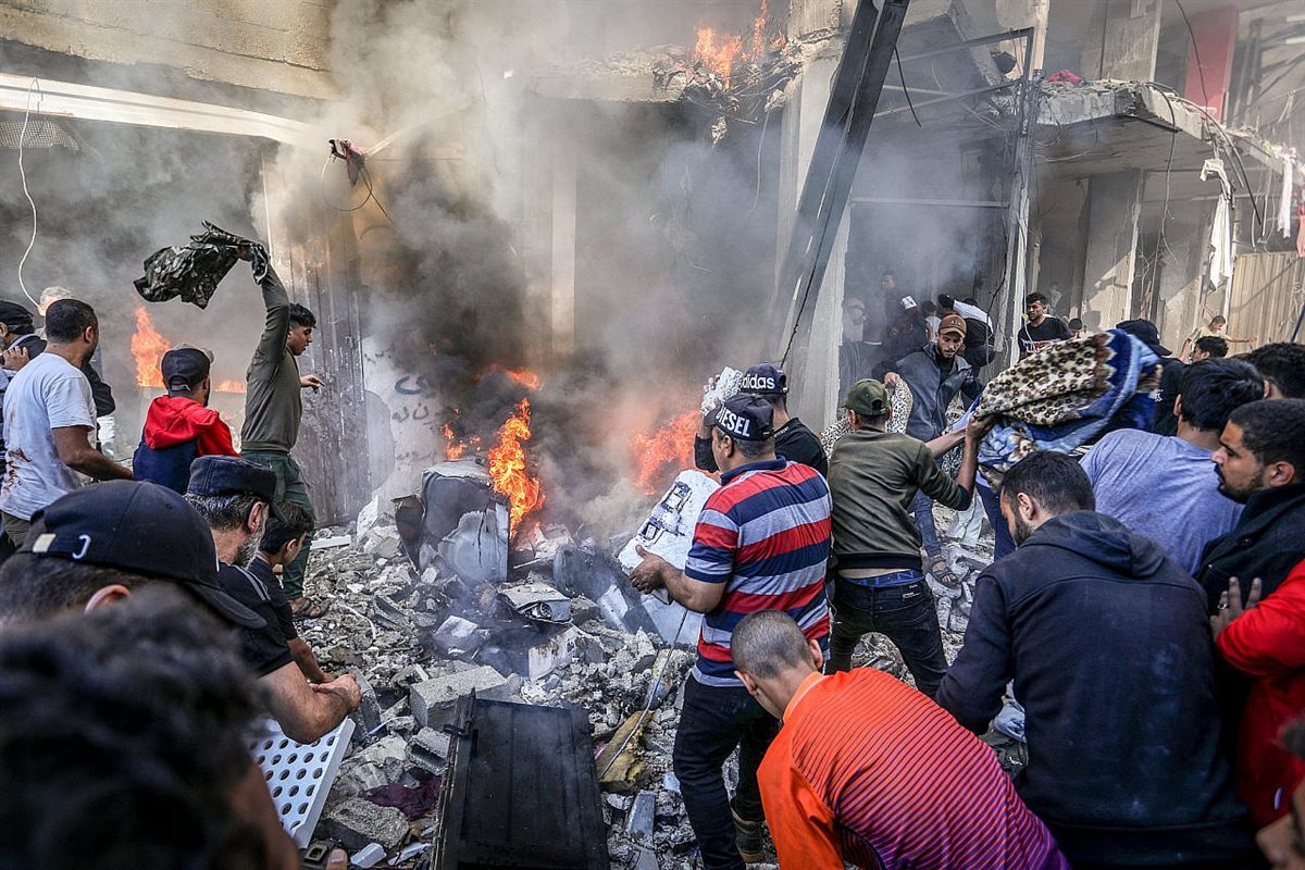 فلسطينيون يحاولون إنقاذ الجرحى وإخماد حريق اندلع بعد غارة جوية إسرائيلية على منزل في مخيم شابورا للاجئين بمدينة رفح