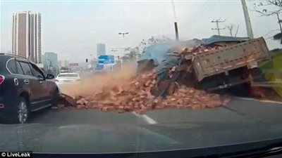 بالفيديو والصور.. حمولة طوب أحمر تدفن سيارة على الطريق بالصين