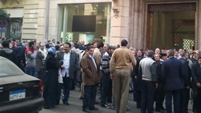 وقفة لموظفي البنك الأهلي بالملابس الرسمية أمام 