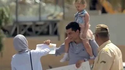 أب يحمل طفلته لمطالبة المارة بتشجيعها على أول رسمة