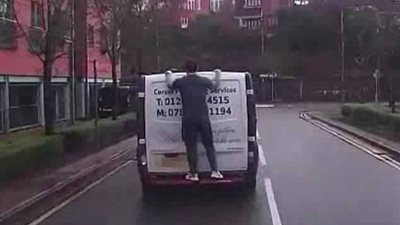 رجل يتعلق بمؤخرة شاحنة على الطريق (فيديو وصور)