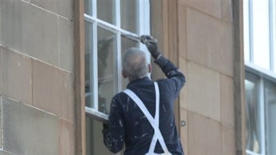 شاهد.. «نقاش» عجوز يخاطر بحياته بالوقوف على حافة شباك