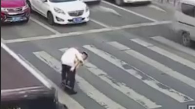 شرطي مرور يحمل رجلا مسنا على ظهره لعبور الطريق (فيديو)