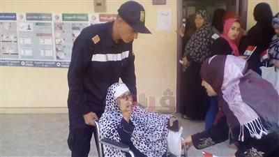 فرد أمن يساعد مسنة للتصويت في الانتخابات بالوراق (صور)