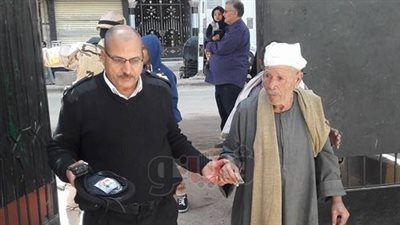 ضابط شرطة يساعد مسنا على الإدلاء بصوته في لجنة فيصل (صور)