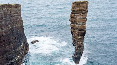 بالصور.. مغامرون يتسلقون كتلة صخرية مرتفعة وسط المحيط