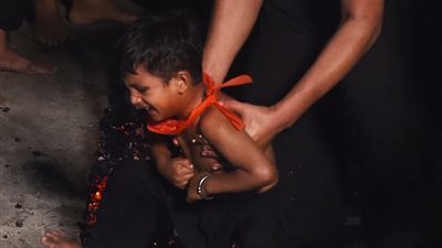 رجل يجبر ابنه على السير فوق الجمرات المشتعلة باحتفالات الشيعة (فيديو وصور)