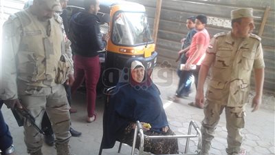 رئيس لجنة ورجال الأمن يحملون عجوزا للتصويت في أرض اللواء (صور)