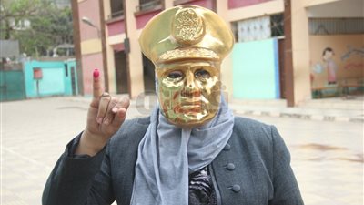 سيدة ترتدي قناعا ذهبيا لوجه السيسي بإحدى لجان الدقي