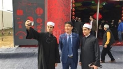 صينيون بمعرض الكتاب يلتقطون السيلفي مع طلاب بالزي الأزهري