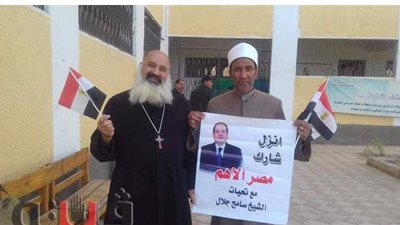 قس وشيخ يرفعان لافتة تحمل صورة السيسى من أجل حث المواطنين على التصويت بالمنيا
