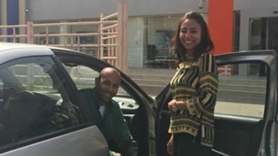 موظفة بـ«CIB» تقدم خدمات البنك لعميل من ذوي الاحتياجات في السيارة