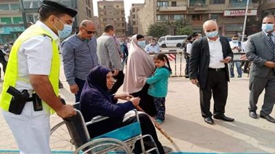 رجال الشرطة يساعدون مسنة للإدلاء بصوتها في لجنة بالقليوبية