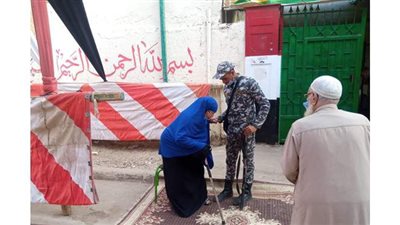 مجند يساعد مسنًّا على ارتداء الكمامة والتصويت في لجنة القناة بالمعادي | فيديو
