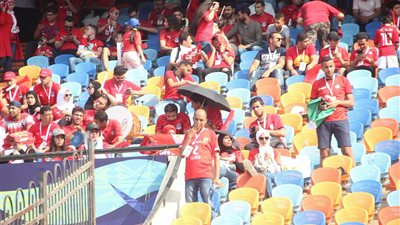 «الشماسي والكراتين» وسيلة جماهير إستاد القاهرة لمواجهة الحر (صور)