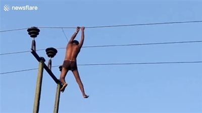 مخمور يتسلق برج كهرباء ويتأرجح بالأسلاك (فيديو)
