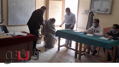 رئيس لجنة يساعد مريضا للتصويت في جولة الإعادة ببني سويف
