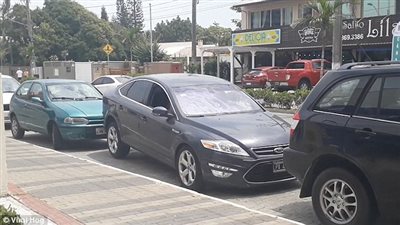 امرأة تخرج من بين سيارتين بخدعة غير متوقعة (فيديو وصور)