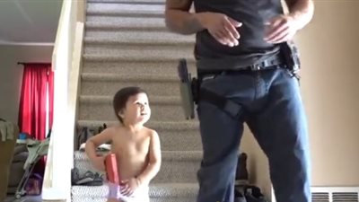 بالفيديو.. أب يعلم ابنه الرضيع استخدام السلاح