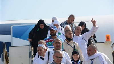 معتمر يلوّح بشارة النصر عقب وصوله مطار القاهرة