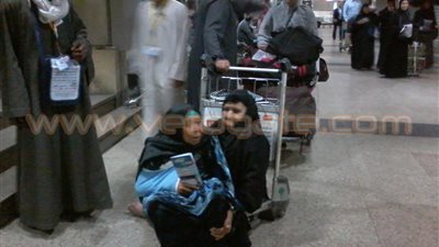 بالصور.. نقل كبار السن على عربات الحقائب بمطار القاهرة