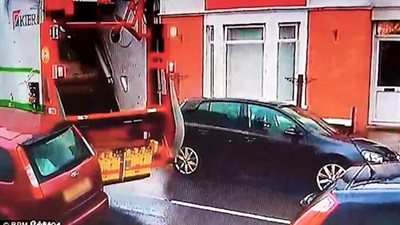 سائق شاحنة قمامة يحطم سيارة متوقفة (فيديو)