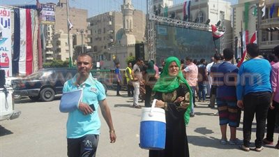 مواطنة توزع الماء المثلج على المحتفلين بقناة السويس في الفيوم