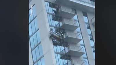 لحظة اشتعال النيران في رافعة تنظيف زجاج بمبنى شاهق الارتفاع (فيديو )