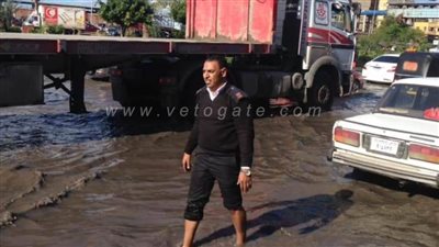 أمين شرطة ينزل في مياه الأمطار لدفع السيارات المعطلة بالإسكندرية (صور)