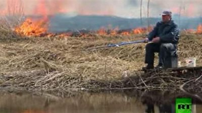 رجل يواصل صيد الأسماك رغم حريق يقترب منه | فيديو