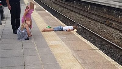 رجل يعرض طفله لخطر الموت على شريط السكك الحديدية (صور)