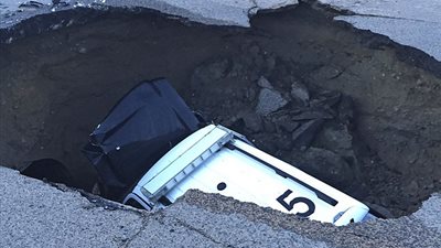 حفرة تبتلع سيارة تقودها امرأة (فيديو وصور)