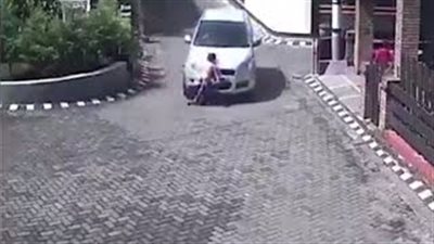 بالفيديو والصور.. طفلة تنجو من الموت بعد دهسها أسفل سيارة