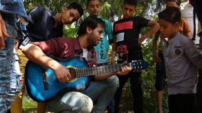 بالفيديو والصور.. شاب يجذب أطفال حديقة الفسطاط بعزفه على الجيتار