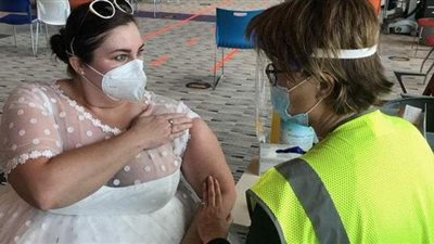 أمريكية تتلقي لقاح كورونا بفستان الزفاف