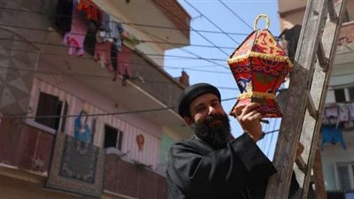 راعي وعمال كنيسة يعلقون زينة رمضان بالقليوبية