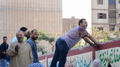 بالصور.. أولياء أمور يراقبون أبناءهم من خلف أسوار المدارس