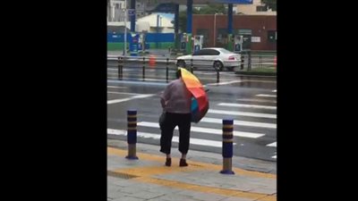 امرأة تدخل في عراك مع مظلتها بسبب الرياح (فيديو)