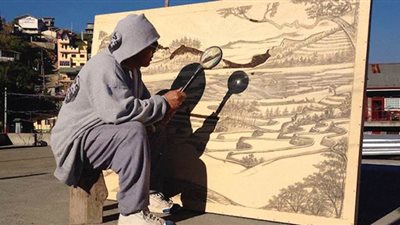 بالصور.. فنان يرسم بأشعة الشمس