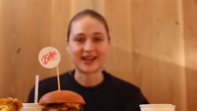 فتاة تتناول «ساندوتش برجر» من 10 طبقات في دقائق (فيديو)