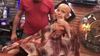 «حلاق السعادة».. مُصفف شعر يرسم البسمة على وجوه أطفال السرطان (فيديو)