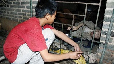 بالصور.. صيني يشتري زوجته من سوق العبيد ويحبسها في قفص