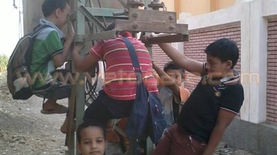 بالصور.. تلاميذ مدرسة ابتدائية بجرجا يتسلقون أعمدة الضغط العالي