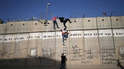 «في طريق البحث عن الأهل».. فلسطيني يتسلق «الجدار العازل» لدخول القدس.. (صور)