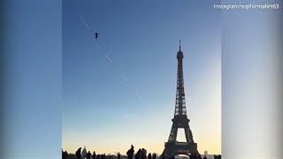 متهور يسير أعلى حبل معلق ببرج إيفل وسط الحشود (فيديو وصور)