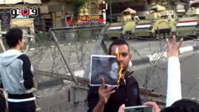 بالفيديو.. أهالي الشهداء يشعلون النيران في صور مبارك بالتحرير