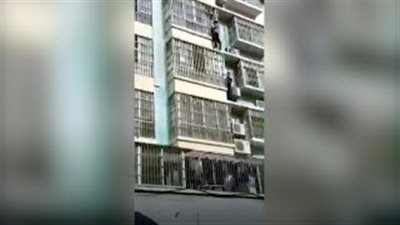 رجلان يتسلقان مبنى لإنقاذ طفل يتدلى من مبنى في مشهد بطولي (فيديو)