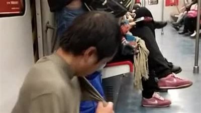 بالفيديو والصور.. متسول يكشف عن خدعته أمام ركاب مترو بالصين
