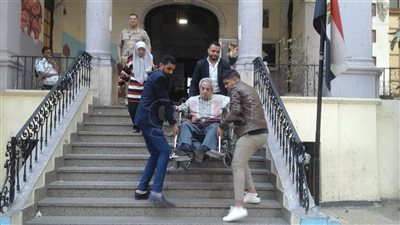 الشرطة تحمل ناخبا بكرسي متحرك للإدلاء بصوته في استفتاء الدستور (صور)